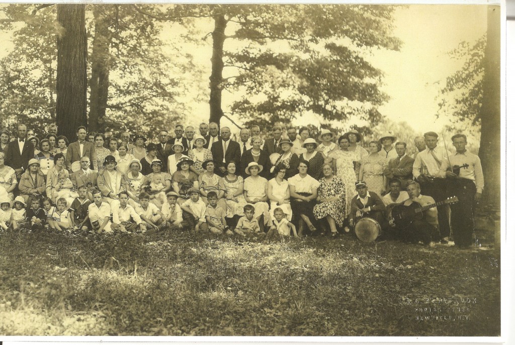 Right side of the Schaber's Grove Community Picture. Pictured are approximately over 100 people on the grass in front of some trees.